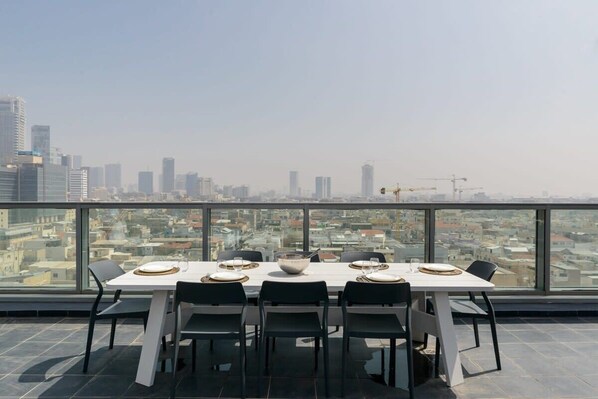 A dining table with chairs and a view of a cityscape through large windows.