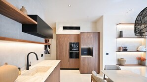 Une cuisine moderne avec des meubles en bois, un four encastré et un réfrigérateur noir.