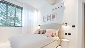 Une chambre moderne avec un grand lit, une table de chevet et un climatiseur fixé au mur.