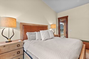 A bedroom with a large bed, wooden headboard, bedside lamps, and a wooden dresser with drawers. - Charming mountain retreat in Silverthorne - Newly built! (Silverthorne)
