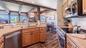 A modern kitchen with wooden cabinets, stainless steel appliances, and a large island. - Walk to Gondola | Cozy 2BR Condo | Pool, Hot Tubs and Fireplace! (Steamboat Springs)