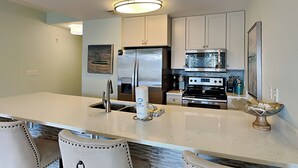 Una cocina moderna con una isla central, electrodomésticos de acero inoxidable y un ventanal grande.