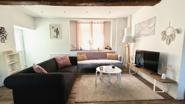 A modern living room with a sofa, a coffee table, a TV, and a window with curtains. - L'Escapade de Pierrefonds by Your Sweet Loc (Pierrefonds)