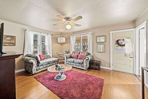 Ein Wohnzimmer mit zwei gemusterten Sofas, einem Couchtisch und einem Deckenventilator.