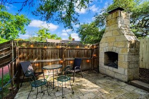 Une terrasse extérieure dotée d’une cheminée en pierre, d’une clôture en bois et de mobilier d’extérieur.