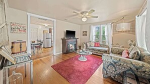 Un salon spacieux doté d’une cheminée, d’un ventilateur de plafond et d’une grande fenêtre.