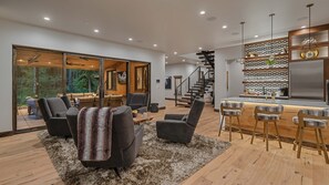 Una sala de estar moderna con un ventanal grande, una chimenea y un comedor con taburetes de bar.