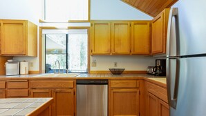 A kitchen with wooden cabinets, a stainless steel dishwasher, and a refrigerator.