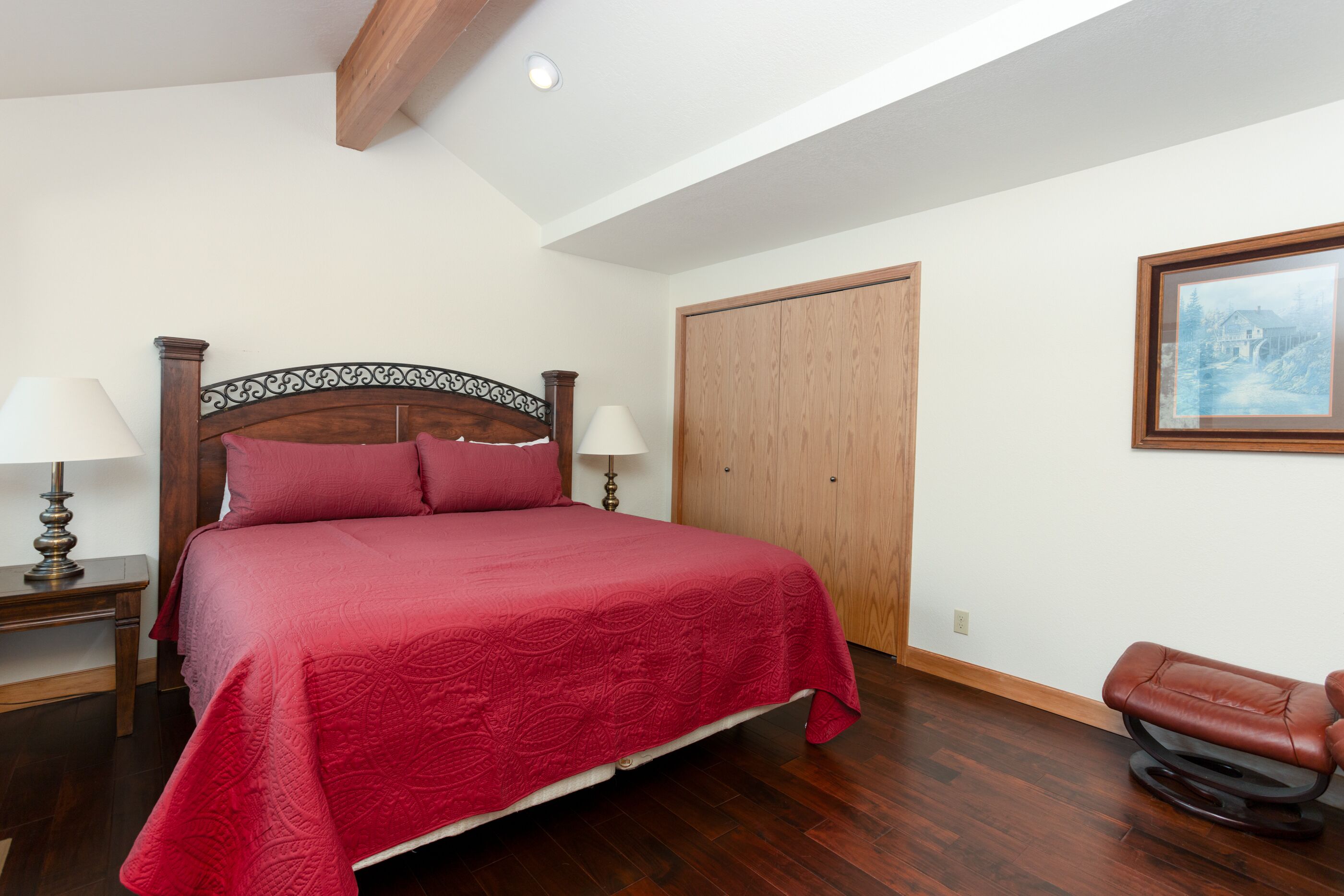 Un dormitorio con una cama de madera, dos lámparas de noche, un armario de madera y una silla de masaje.