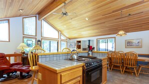 A spacious kitchen with wooden cabinets, a gas stove, and a dining area with wooden chairs.
