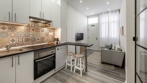 A modern kitchen with a tiled backsplash, a built-in oven, and a bar area with stools. - Waou Fresh Confort I (Madrid)