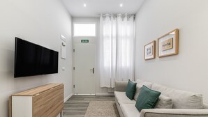 A modern hotel lobby with a flat-screen TV, a reception desk, a sofa with cushions, and framed artwork on the wall. - Waou Fresh Confort I (Madrid)