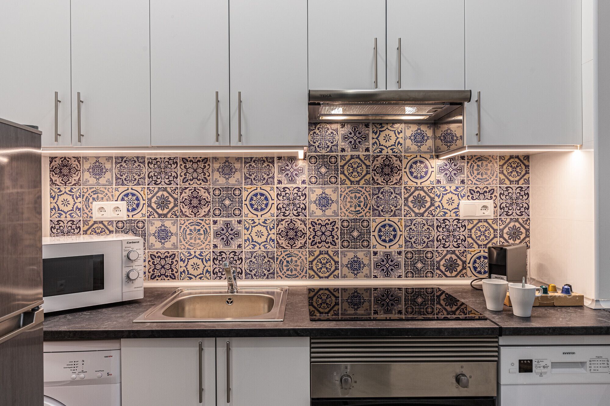 A kitchen with white cabinets, a stainless steel sink, a microwave, and a dishwasher.