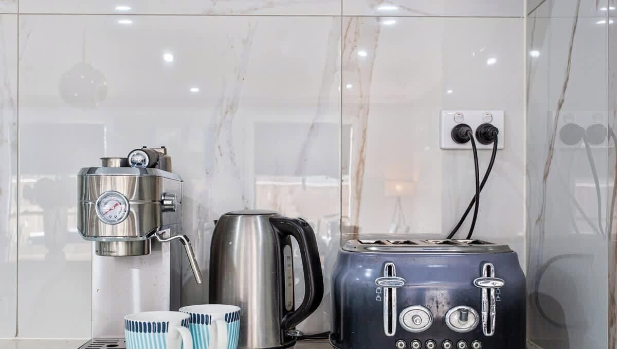 Cucina accessoriata con macchina da caffè, bollitore, tostapane e tazze.