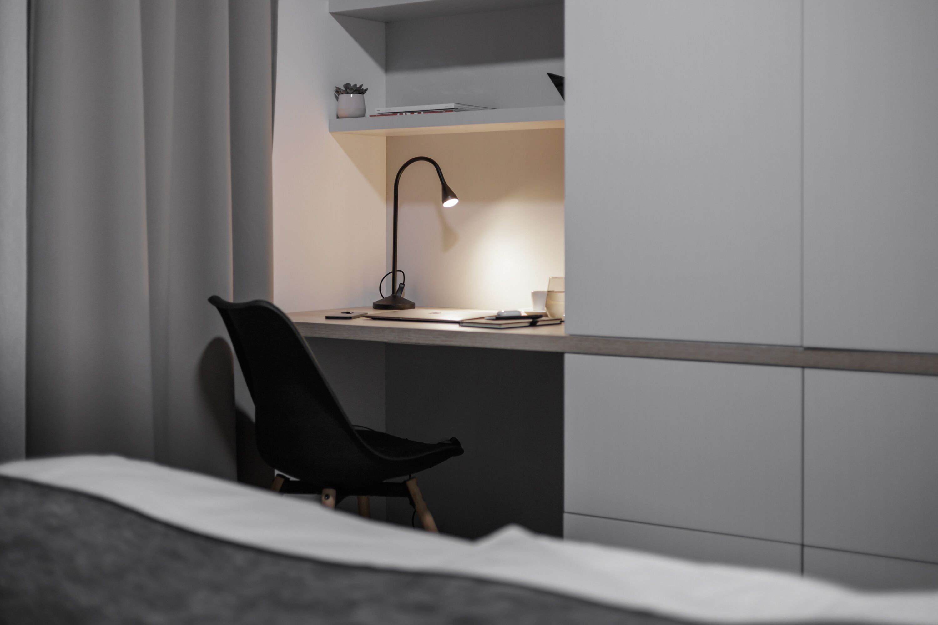 A modern bedroom with a bed, a desk, and a chair.