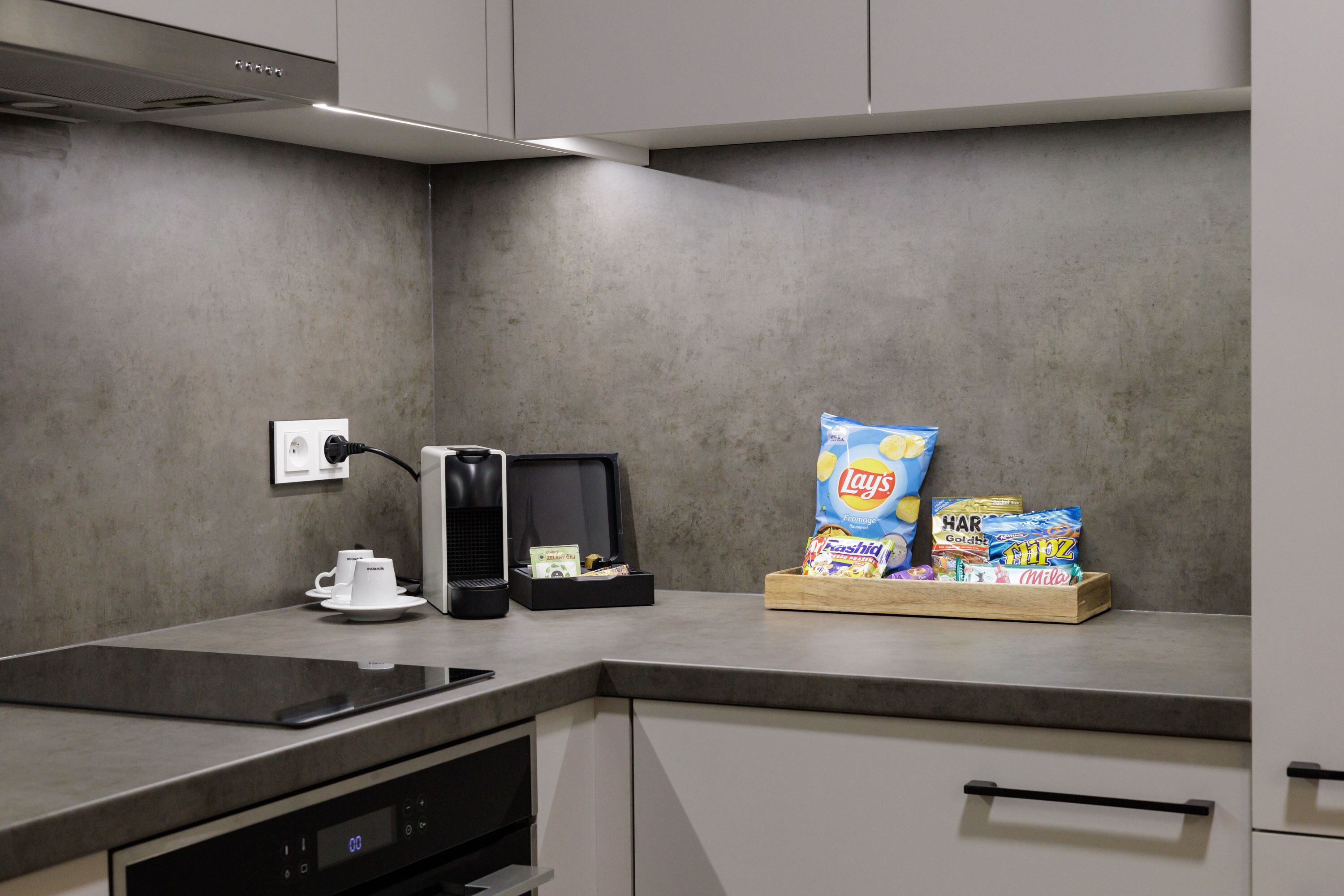 A modern kitchen with a built-in stove, a coffee maker, and a snack bar with chips and other snacks.