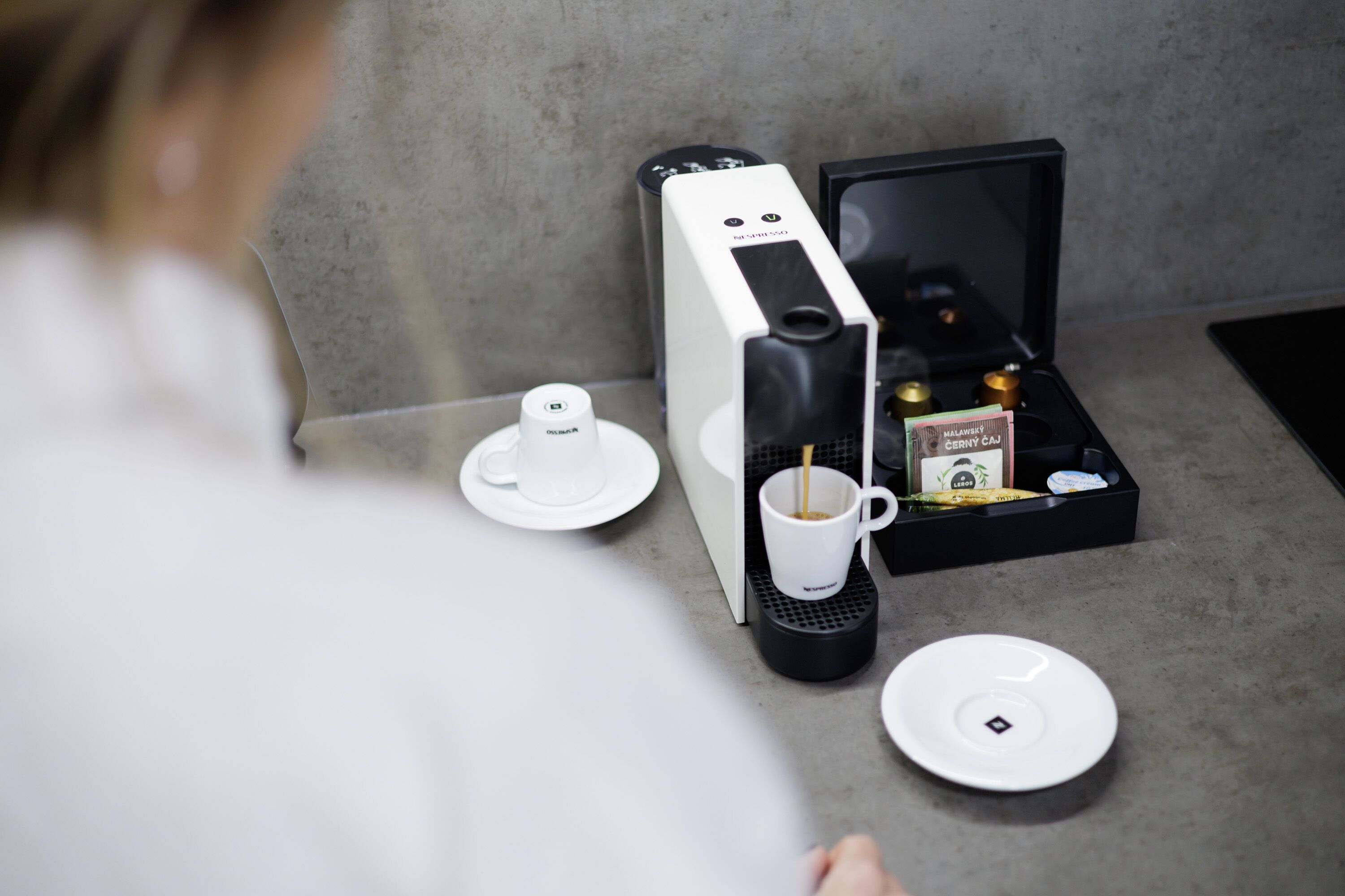 Een koffiemachine met een kop en een dienblad vol koffiepads.