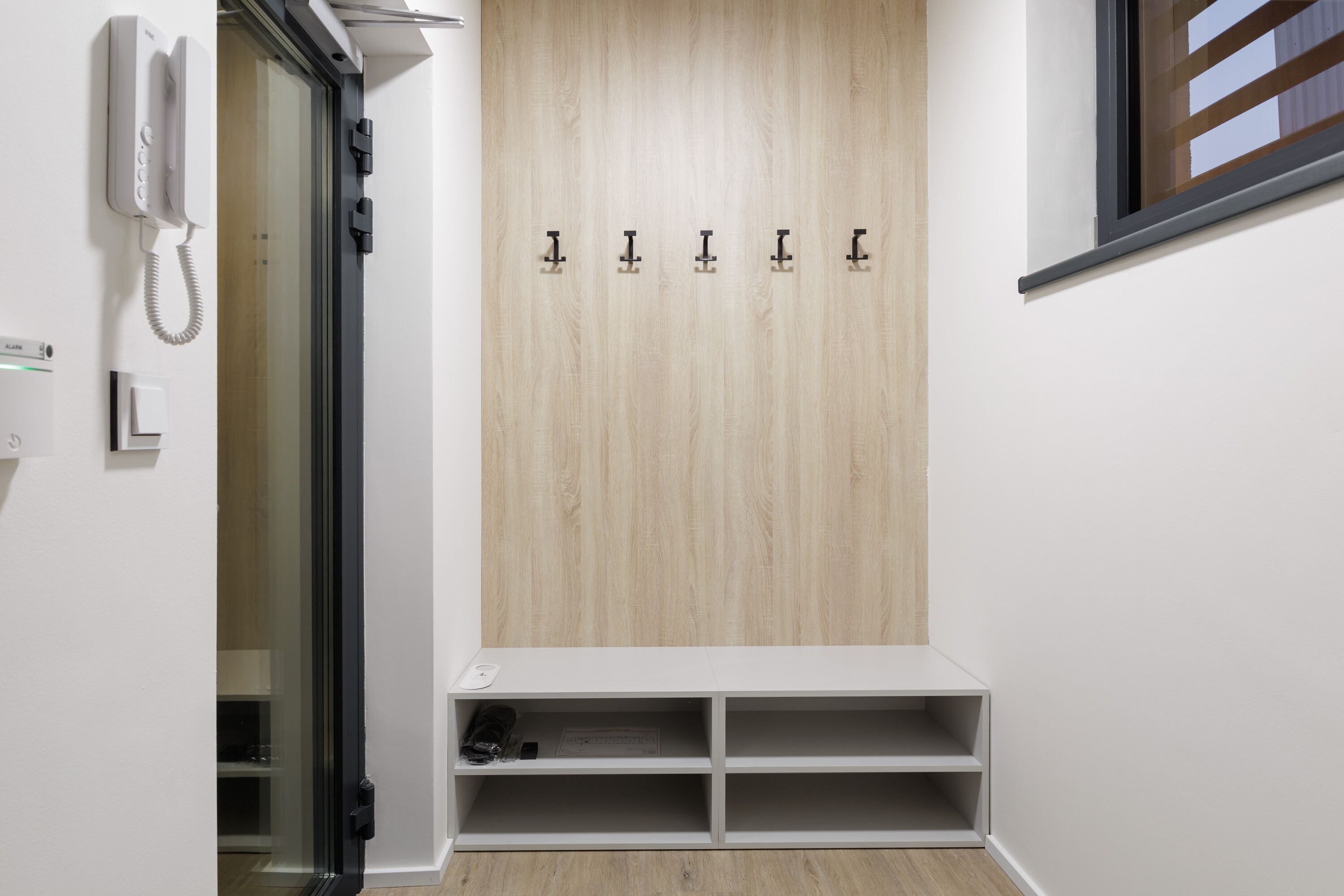 A hallway with a wooden wall, a coat rack, and a phone.