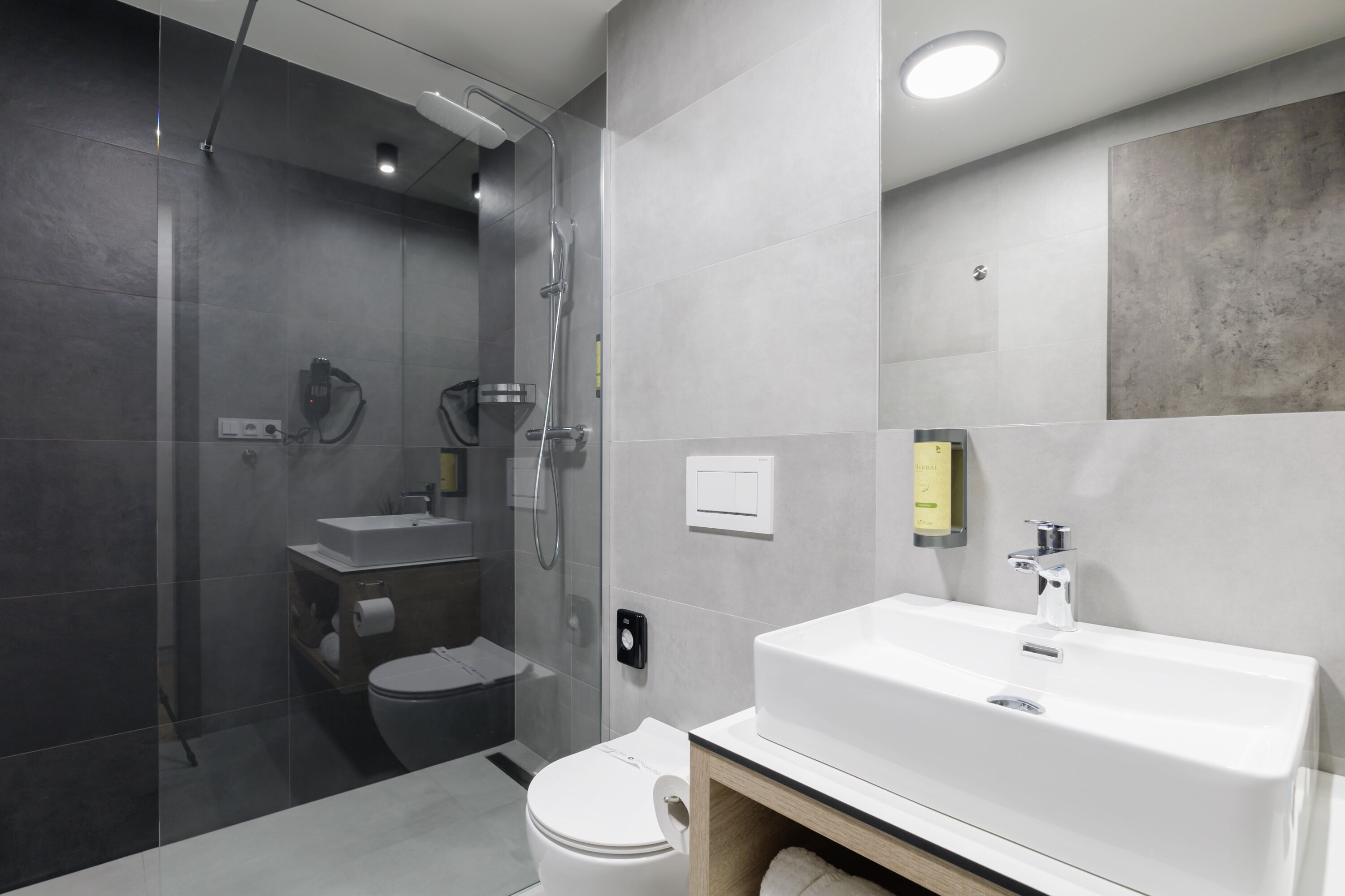 A modern bathroom with a glass-enclosed shower, a white sink, and a toilet.