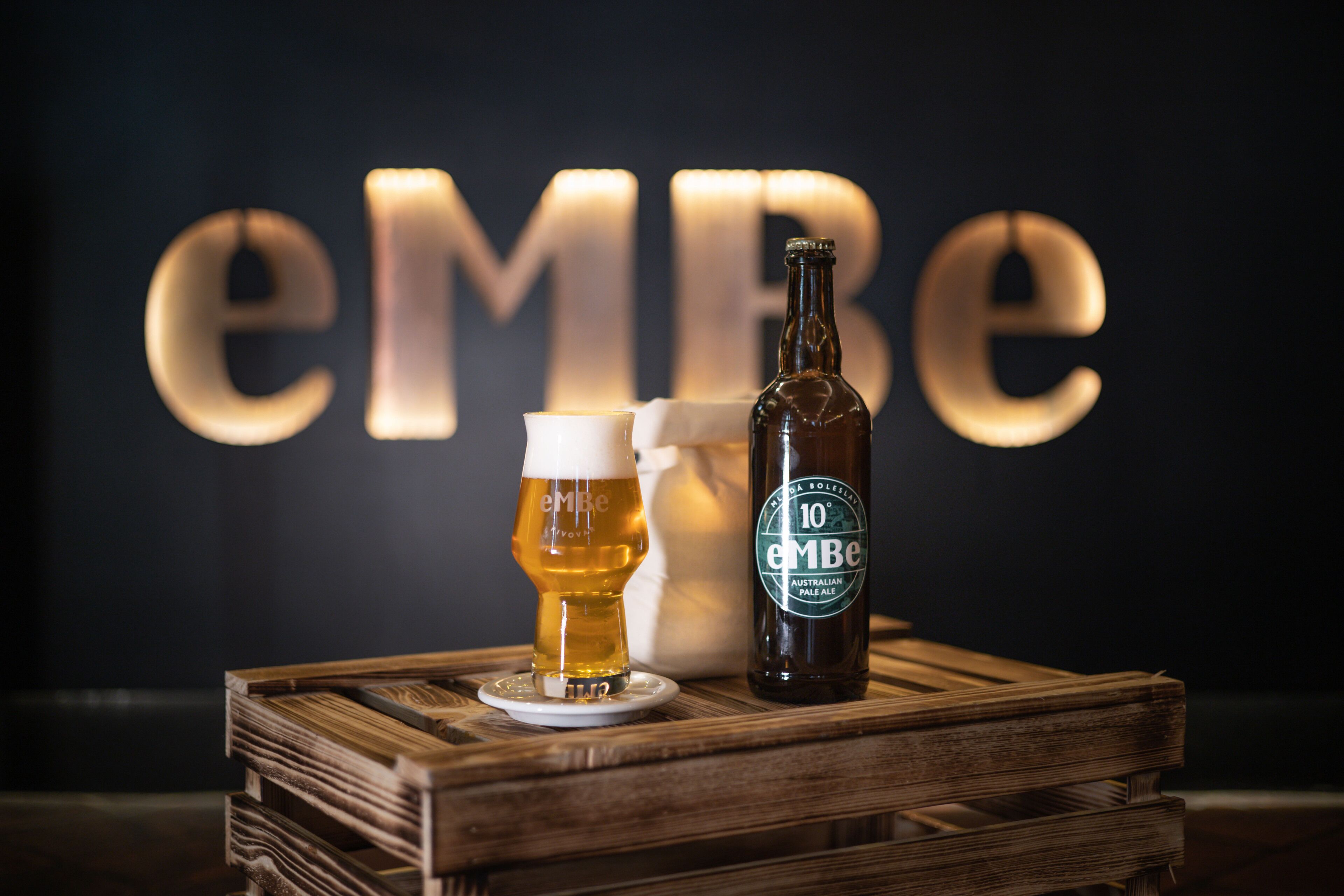 Una botella de Pale Ale australiana eMBE al 10% y un vaso de cerveza sobre un canasto de madera.