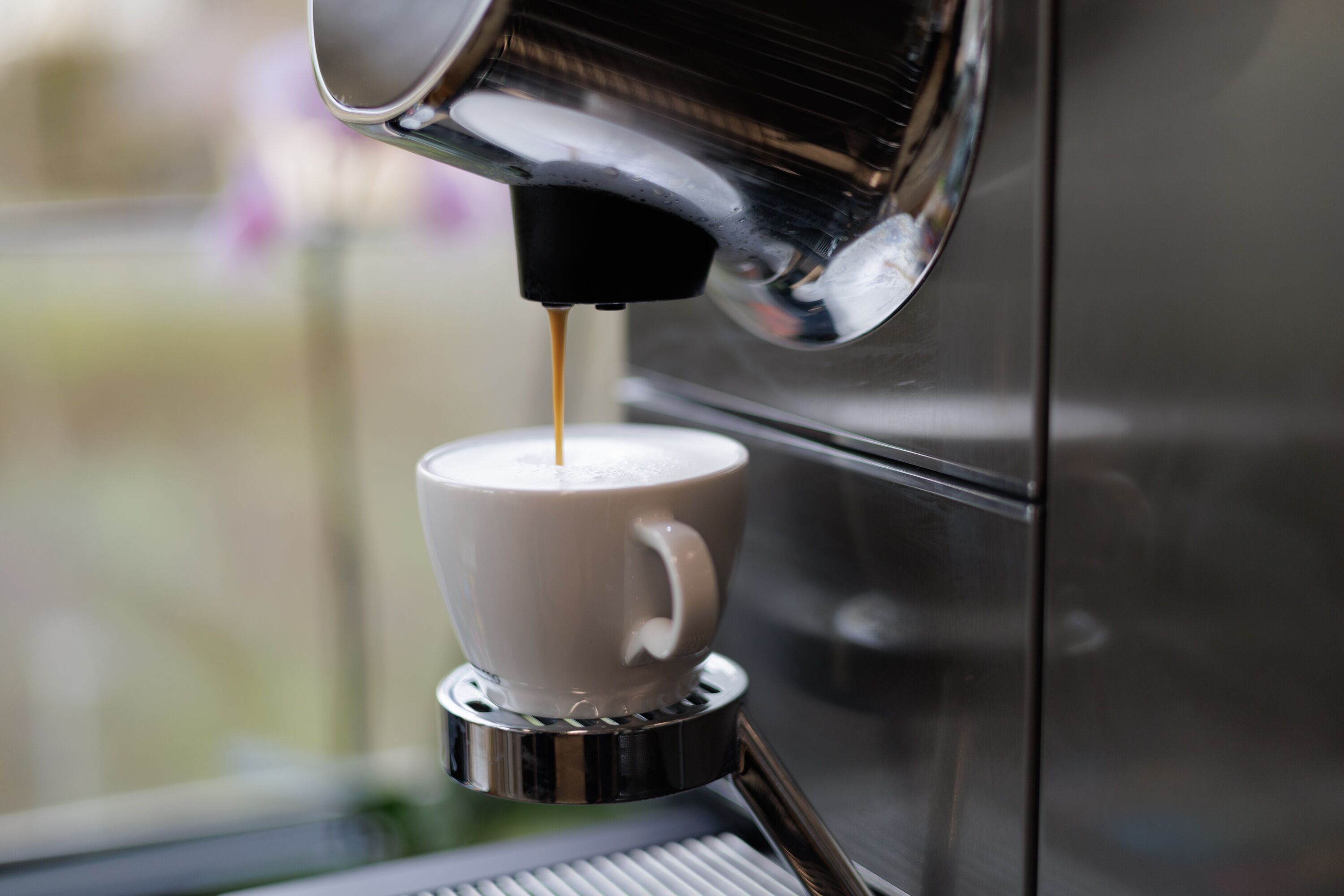 En kaffemaskine serverer kaffe i en kop.