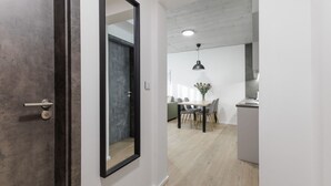 Een modern interieur met een houten vloer, een eethoek met tafel en stoelen, en een keuken met aanrecht en kasten.