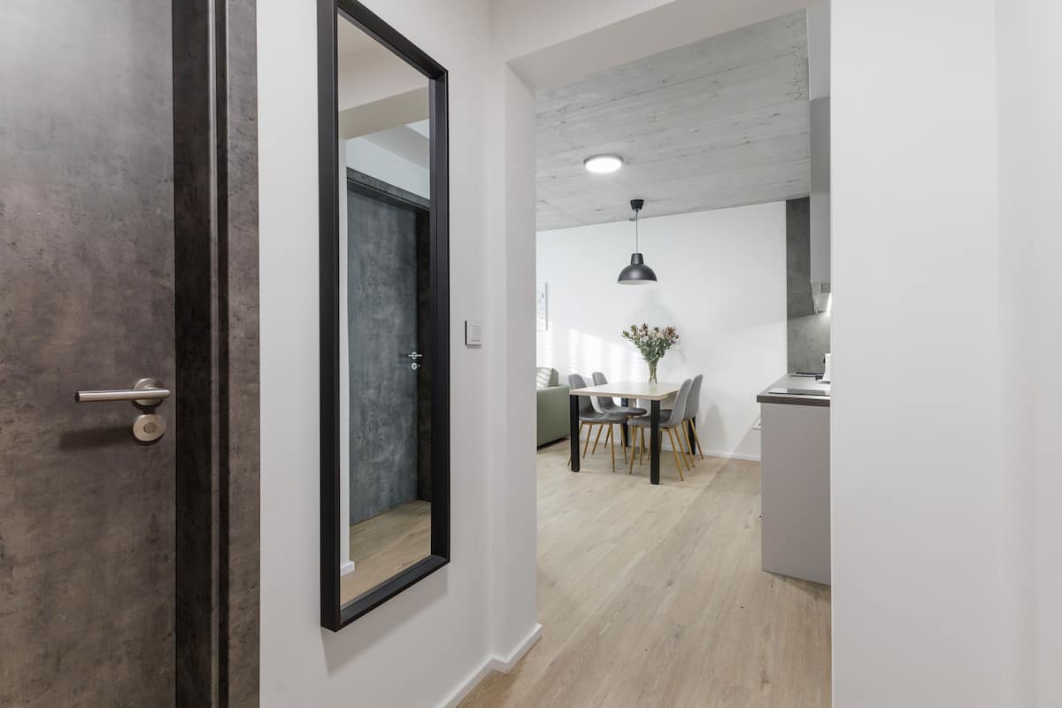 Un intérieur moderne avec un plancher en bois, un coin repas comprenant une table et des chaises, et un espace cuisine doté d’un comptoir et d’armoires.