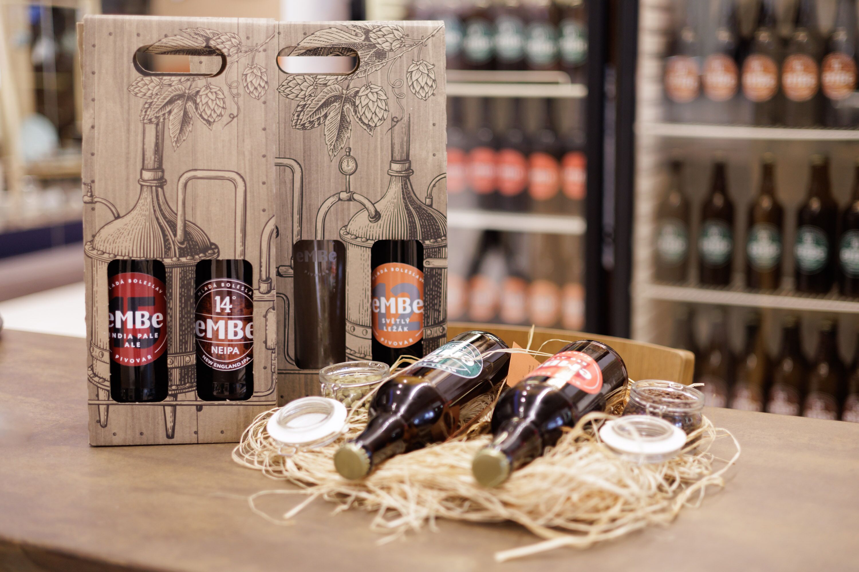 A wooden box with bottles of 'EMBE' beer, a bottle of 'India Pale Ale', and a bottle of 'Neipa'.