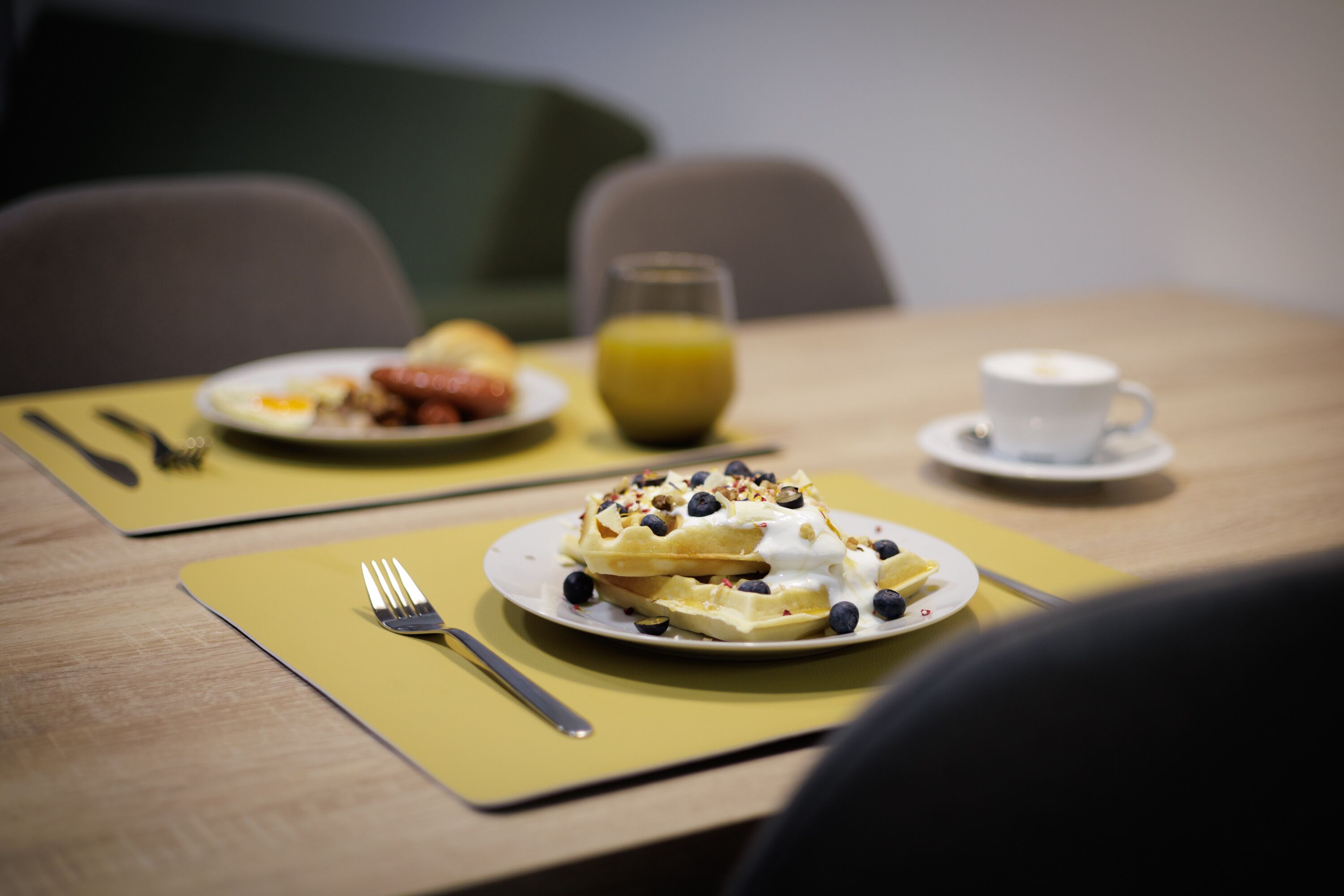 Una mesa con waffles, fruta y una taza de café para el desayuno.