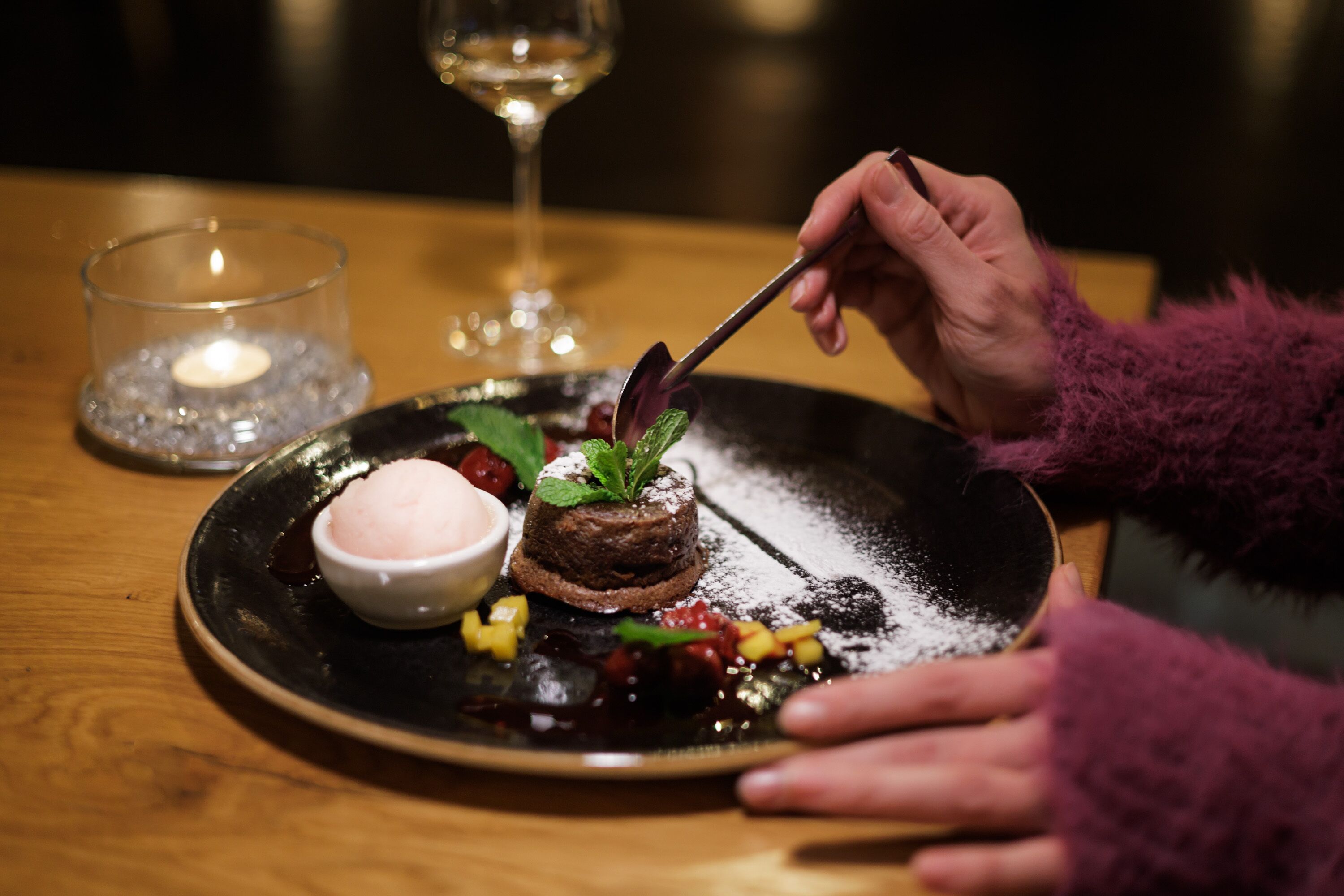 Ein Dessertteller mit Schokoladenkuchen, Minzblättern und Puderzucker.