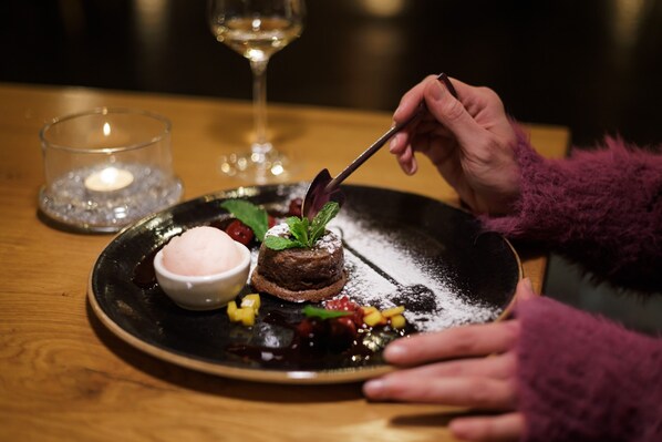 A dessert plate with a chocolate cake, mint leaves, and powdered sugar.