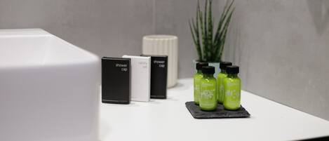A bathroom with a white sink, a vanity set, and three green herbal bottles on a black mat.