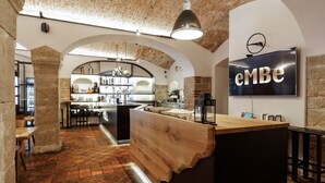 Een moderne bar met een houten toonbank, een gewelfd bakstenen plafond en een televisie waarop 'eMBE' staat.