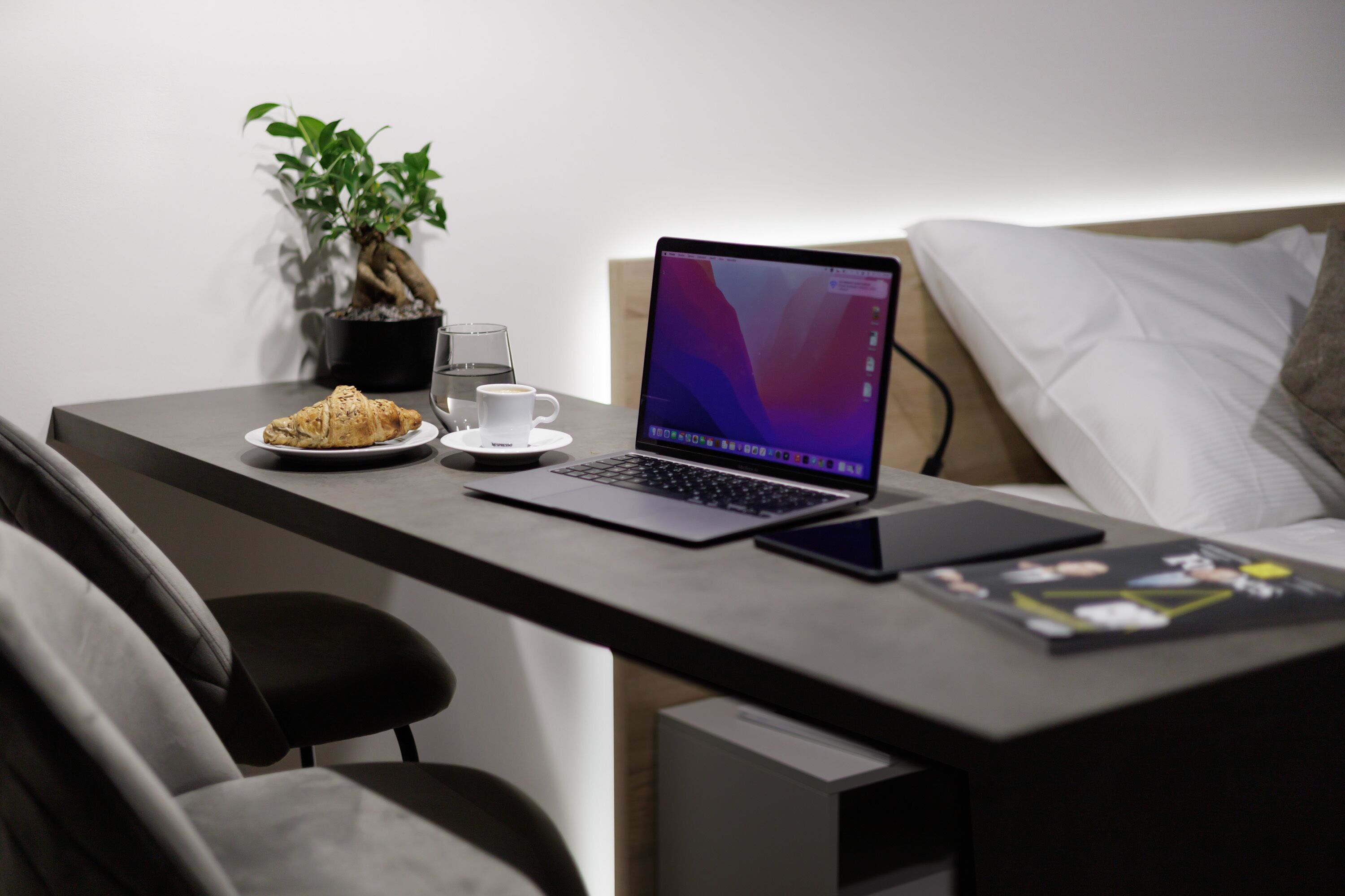 Una camera moderna con una scrivania, un portatile e un letto.
