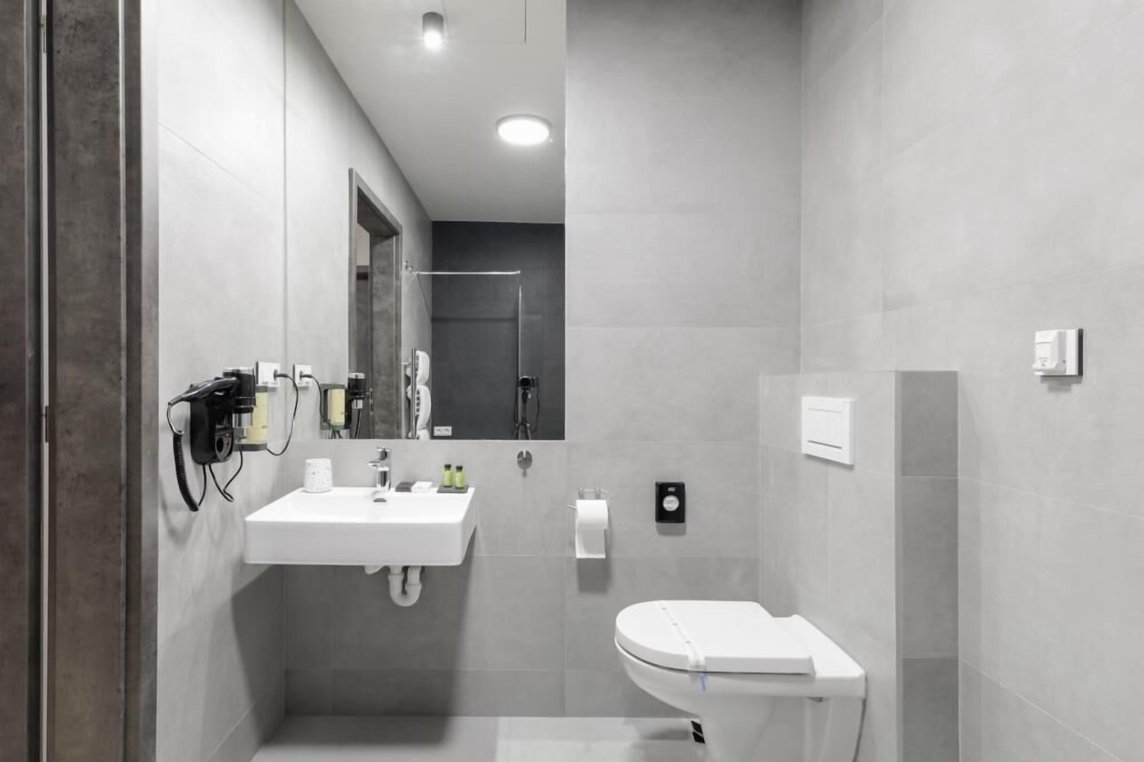 Une salle de bain moderne avec un lavabo blanc, un miroir et des toilettes.