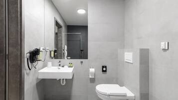 Une salle de bain moderne avec un lavabo blanc, un miroir et des toilettes.