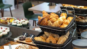 A buffet with various breads, pastries, and jars of spreads.