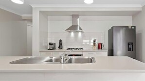 A modern kitchen with a central island, stainless steel appliances, and pendant lighting. - Spacious Cowes Retreat with BBQ & Boat Parking (Cowes)