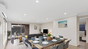 A modern living room with a dining area, a sofa set, a TV, and a painting on the wall. - Spacious Cowes Retreat with BBQ & Boat Parking (Cowes)