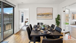 A dining area with a table set for six, large windows, and a painting on the wall. - Getaway for six Accessible accommodation (San Remo)