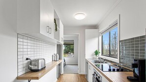 A modern kitchen with white cabinetry, a wooden countertop, a toaster, and a window providing natural light. - Getaway for six Accessible accommodation (San Remo)