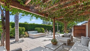 Eine überdachte Terrasse mit Sitzgelegenheiten, einem Whirlpool und einer Pergola mit Lichterketten.