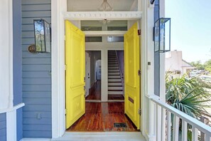 Una escalera de madera conduce a un piso superior, flanqueada por dos puertas abiertas de color amarillo.