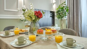 Un desayuno servido en una mesa para dos, con croissants, tartaletas de fruta y zumo de naranja.