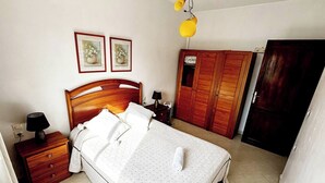 A neatly arranged bedroom with a wooden bed, bedside tables, a wardrobe, and two framed pictures on the wall. - Center city Clean Family Appartement (Tétouan)