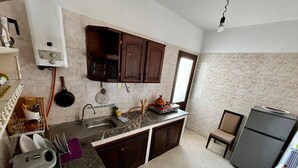 A kitchen with a marble countertop, dark wooden cabinets, a built-in oven, and a refrigerator. - Center city Clean Family Appartement (Tétouan)