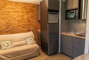 A compact kitchenette with a microwave, oven, and sink.