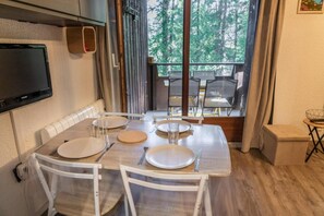 A dining area with a table set for two, chairs, a television mounted on the wall, and a view of the outdoors through a window. - 5th floor, balcony, tv, ski locker, 20m², Les Orres (Les Orres)
