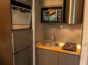 A compact kitchen with a built-in microwave, a stainless steel sink, and a wooden countertop. - 5th floor, balcony, tv, ski locker, 20m², Les Orres (Les Orres)