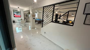 Un intérieur moderne comprenant une table de billard, un coin repas et un escalier.